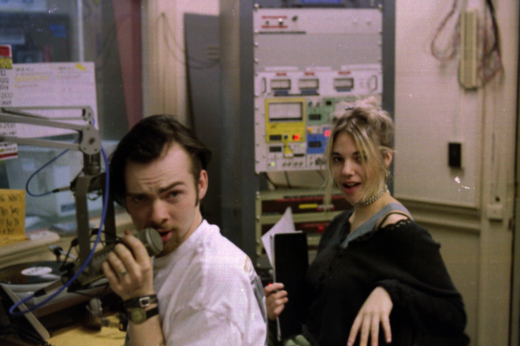 Two students in radio station broadcast booth.