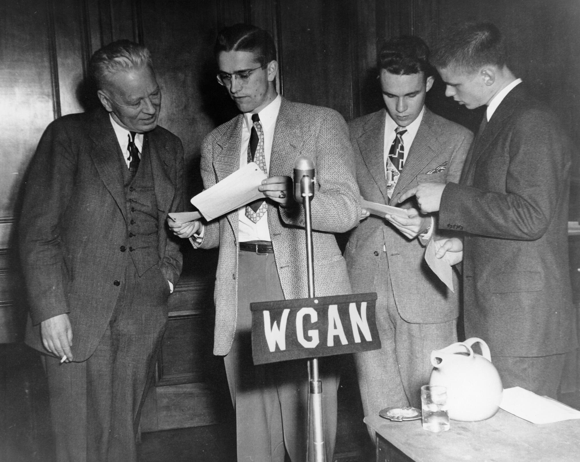 Three students and an adult stand in front of a WGAN microphone.