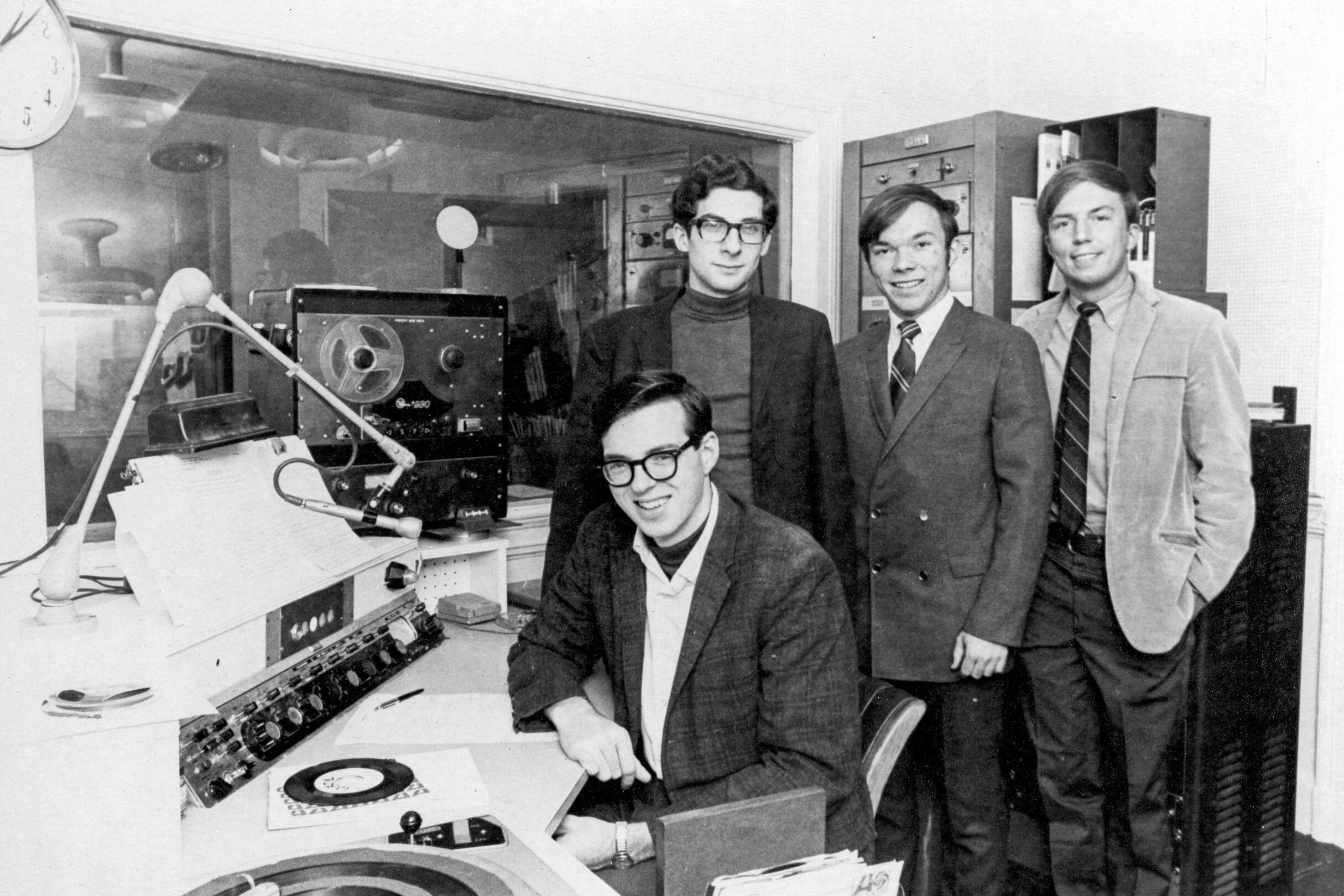 Four students in the WBOR studio, one of which is sitting